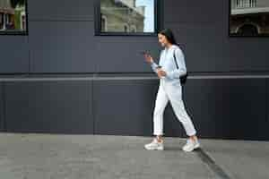 Free photo full shot woman walking with device