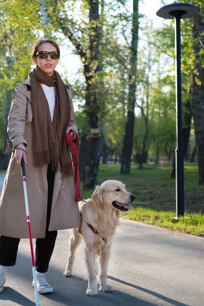 Полный кадр женщина гуляет с собакой и тростью
