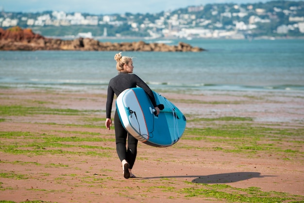 Donna a tutto campo che cammina con il paddleboard