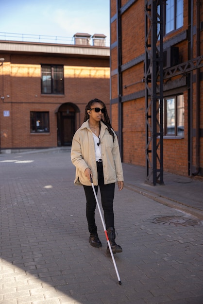 Full shot woman walking with white cane