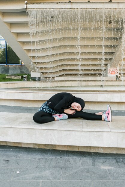 Full shot of woman wearing hijab stretching