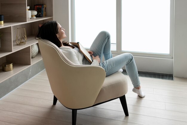 Full shot woman with book on chair