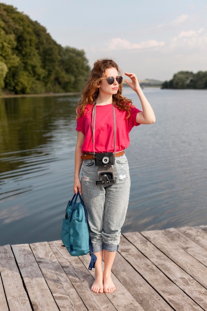 Free photo full shot woman with camera posing on dock