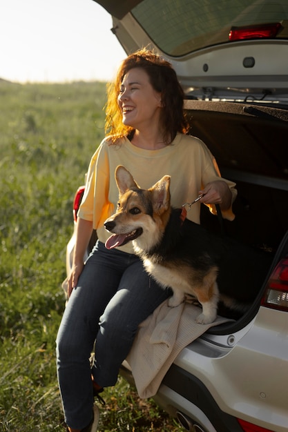 Foto gratuita donna a tutto campo con cane carino e macchina