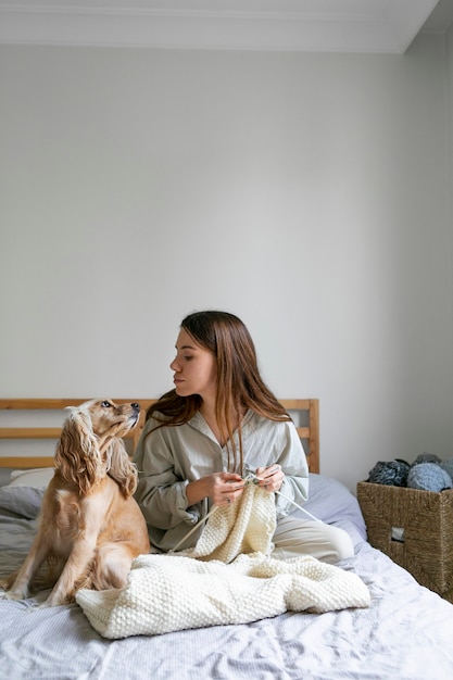 Full shot woman with cute dog knitting