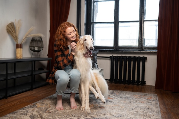 Full shot woman with cute greyhound dog