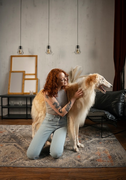 Бесплатное фото Женщина в полный рост с милой борзой собакой