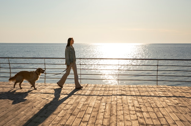 Free photo full shot woman with dog on a jetty