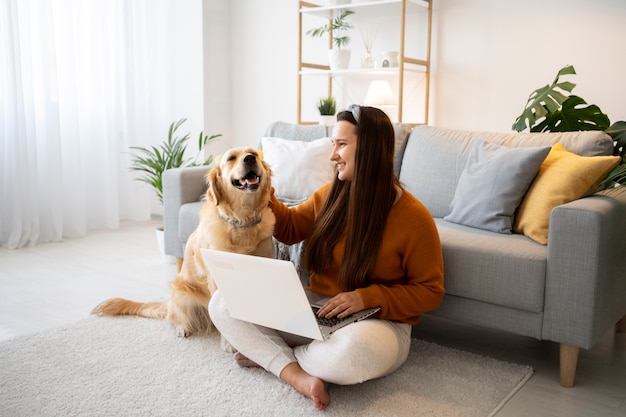 Полный снимок женщины с собакой и ноутбуком