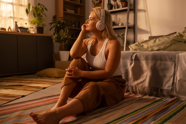 Free photo full shot woman with headphones at home