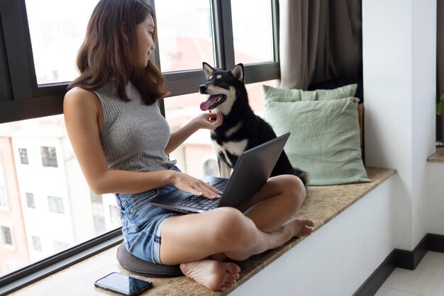 ノートパソコンと犬とフルショットの女性