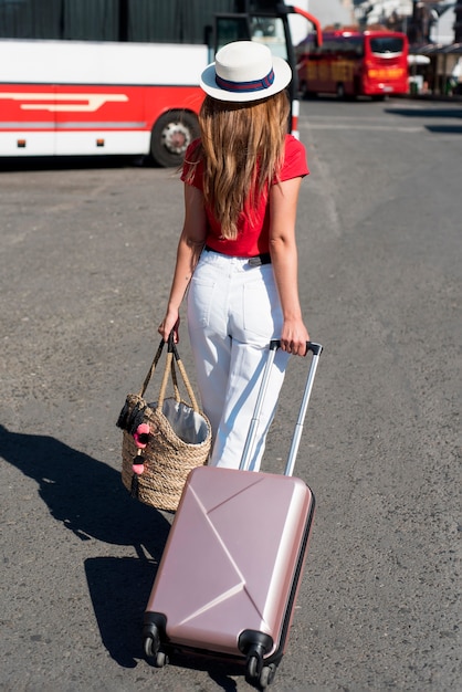 Женщина в полный рост с багажом на автобусной станции