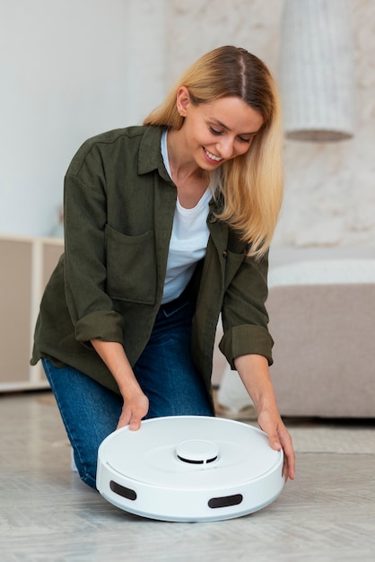 Free photo full shot woman with robotic vacuum cleaner at home