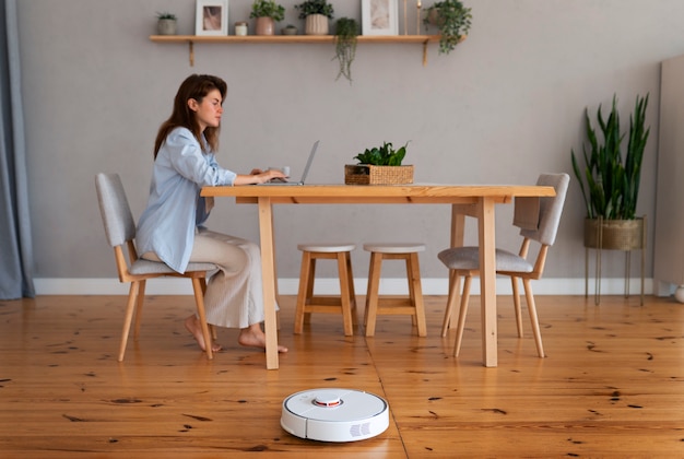 full shot woman with  robotic vacuum cleaner