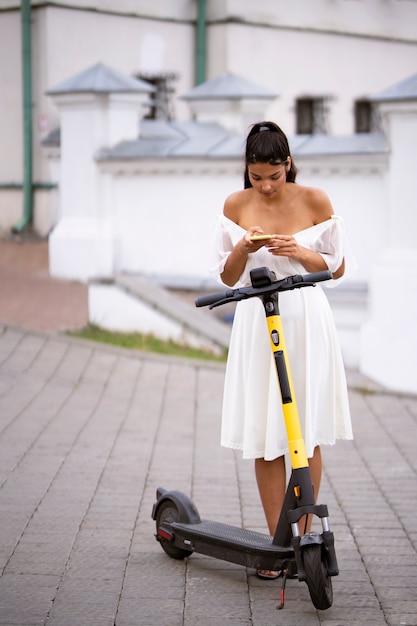 屋外でスクーターを持つフルショットの女性