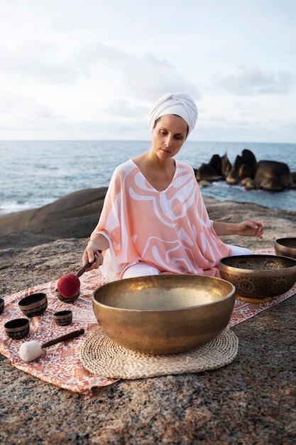 Full shot woman with singing bowls at beach