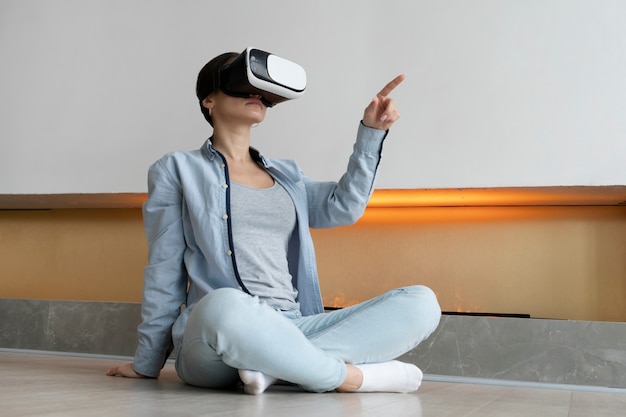 Full shot woman with vr glasses on floor