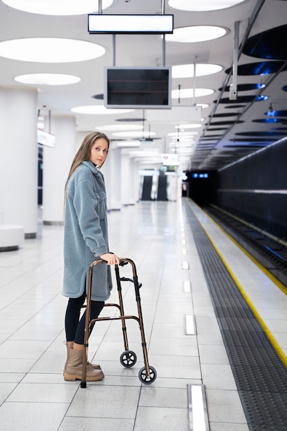 地下鉄駅でウォーキングフレームを持つフルショットの女性