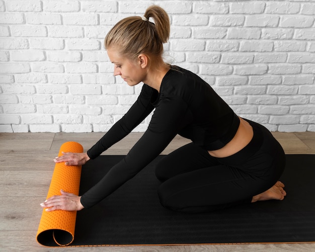 Женщина в полный рост с ковриком для йоги