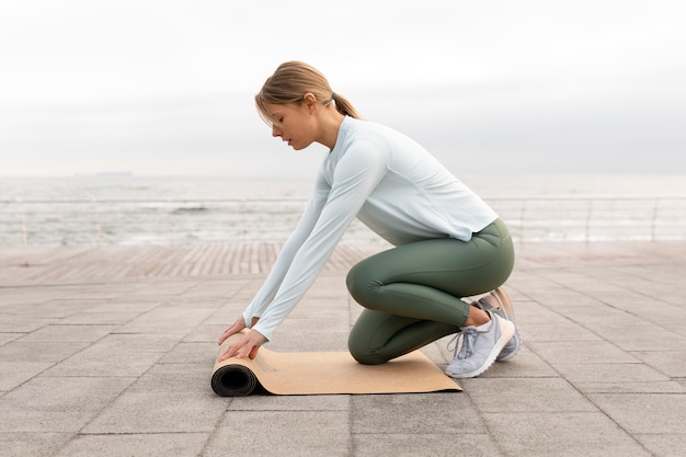 Женщина в полный рост с ковриком для йоги