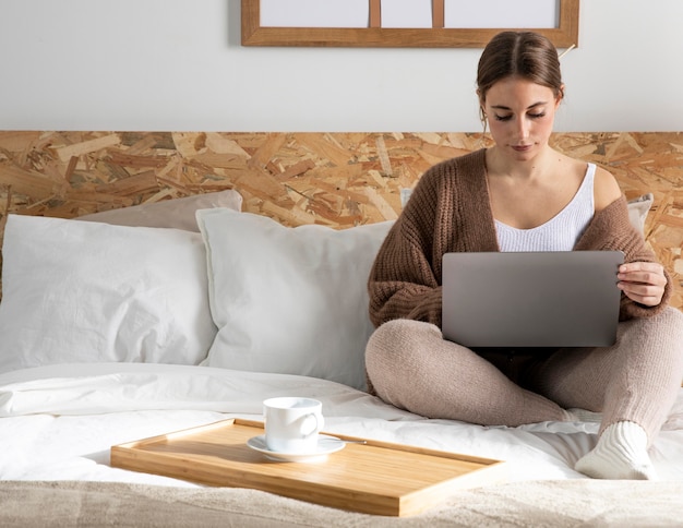 Free photo full shot woman working in bedroom