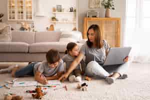 Foto gratuita donna a tutto campo che lavora da casa con i bambini