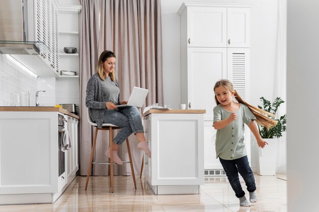 Full shot woman working at home with kid