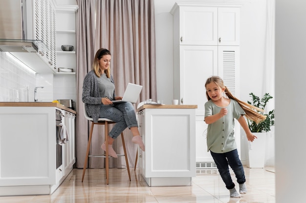 Full shot woman working at home with kid