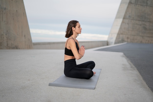 Foto gratuita donna del colpo pieno sulla stuoia di yoga