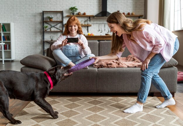 Donne e cane del colpo pieno che si divertono