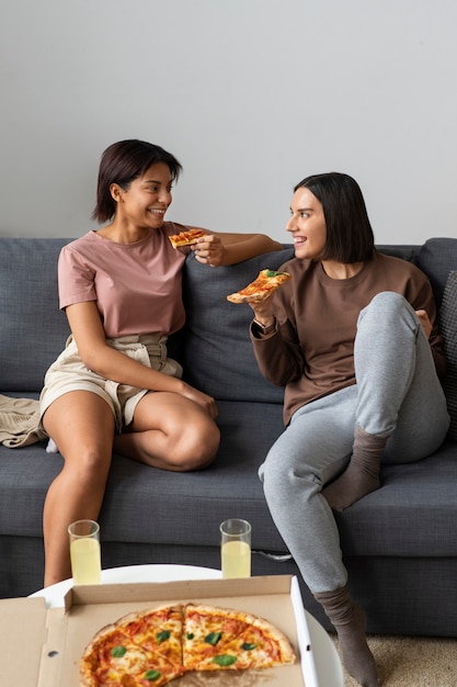 Foto gratuita donne a figura intera che mangiano una pizza deliziosa