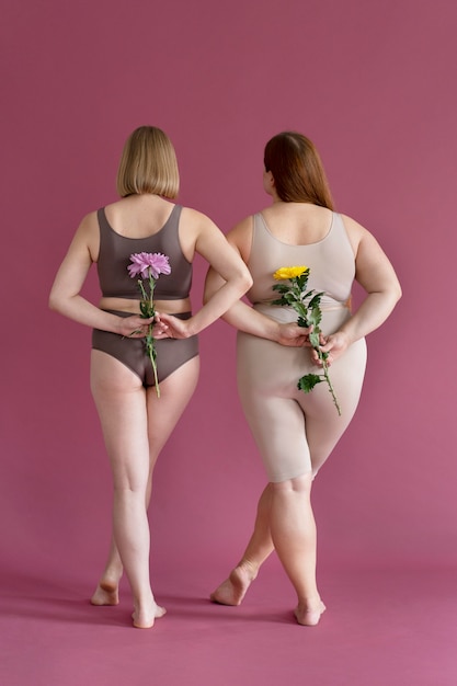 Free photo full shot women holding flowers