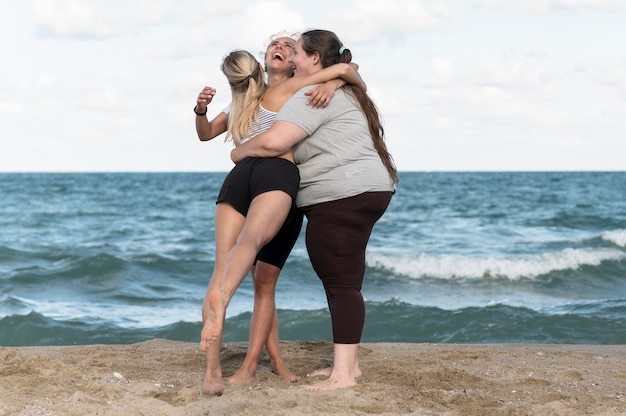 Donne del colpo pieno che abbracciano in riva al mare