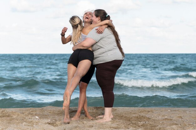 海辺で抱き締めるフルショットの女性