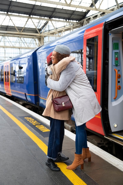 Full shot women hugging at train station