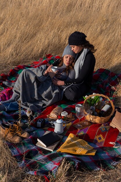 Full shot women laying on blanket outdoors