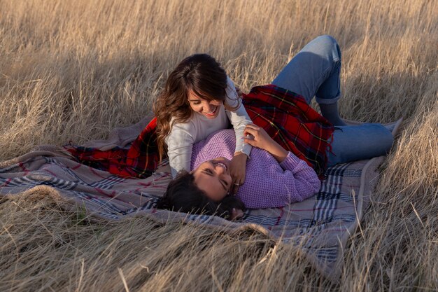 Full shot women laying on blanket outdoors