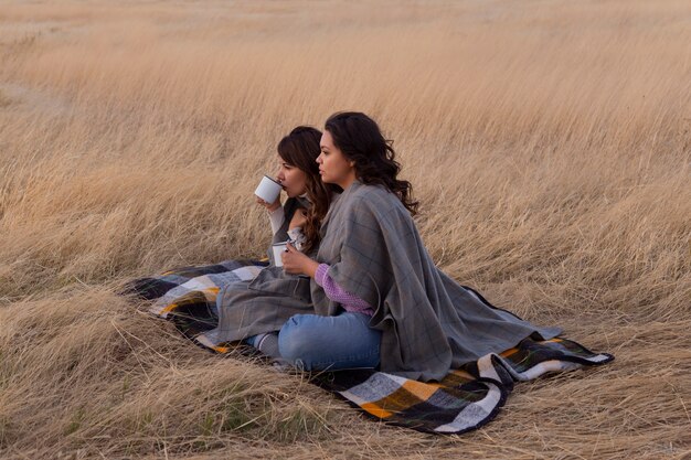 Full shot women laying on blanket outdoors