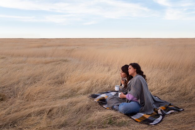 Full shot women laying on blanket outdoors