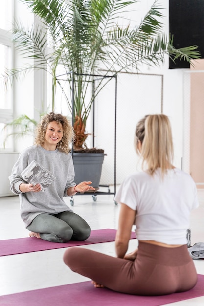 Foto gratuita donne del colpo pieno sulle stuoie nella classe di yoga