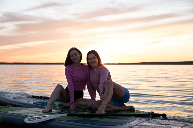 Free photo full shot women paddleboarding