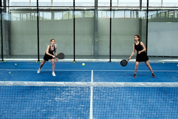 Женщины в полный рост играют в паддл-теннис