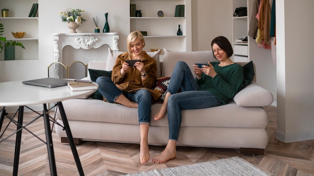 Foto gratuita donne a figura intera che giocano con il telefono