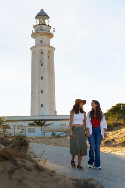 Free photo full shot women posing with lighthouse