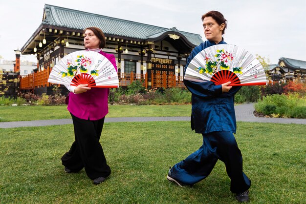 Full shot women practicing tai chi with fans