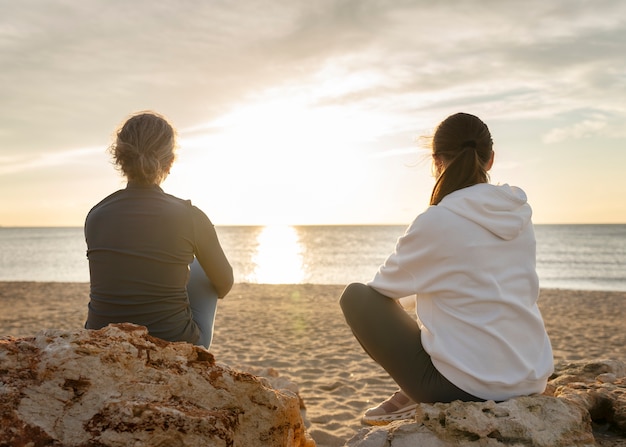 Free photo full shot women sitting on beach