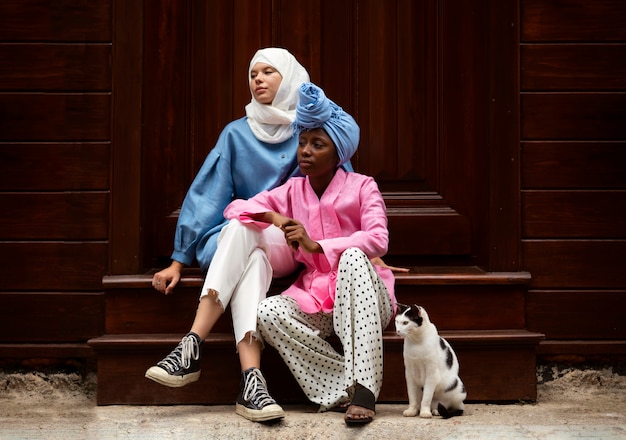 Full shot women sitting on stairs with cat