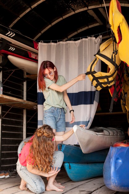 Full shot women taking kayak from shed