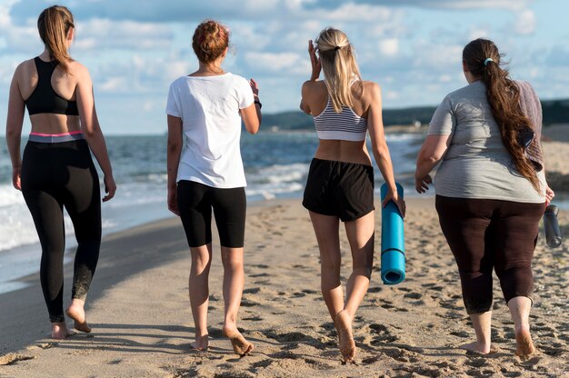 Full shot women walking on shore