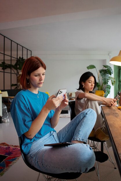 Full shot women with devices indoors
